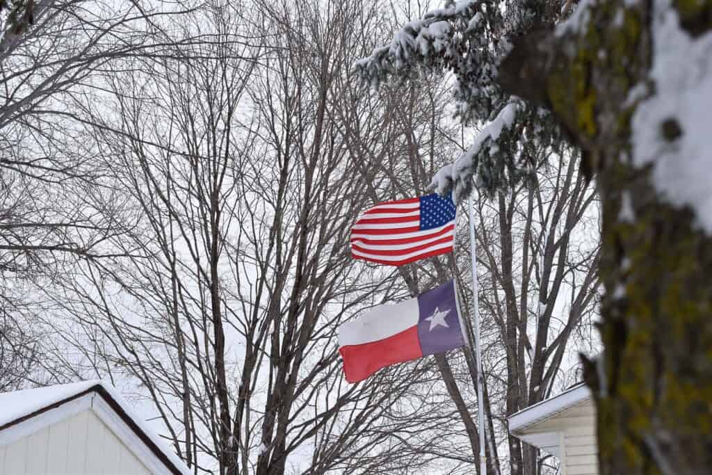USA and Texas flags in the wind and snow